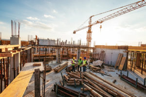 Projektsteuerung - Architekten und Ingenieure diskutieren über den Arbeitsfortschritt zwischen Betonwänden, Gerüsten und Kränen.